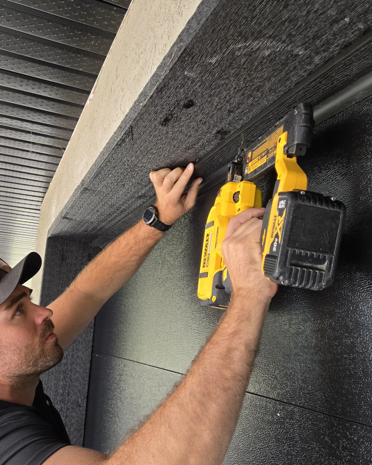 Mark, co-owner of Garage Door Doctor Canada, fastening a new top seal above a garage door with a brad nailer