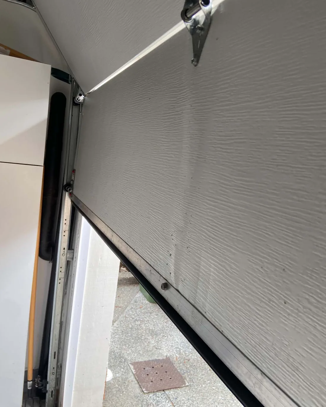 Bottom panel of a garage door at Arbutus Ridge near Mill Bay, creased and pushed out of line after being struck by a reversing car