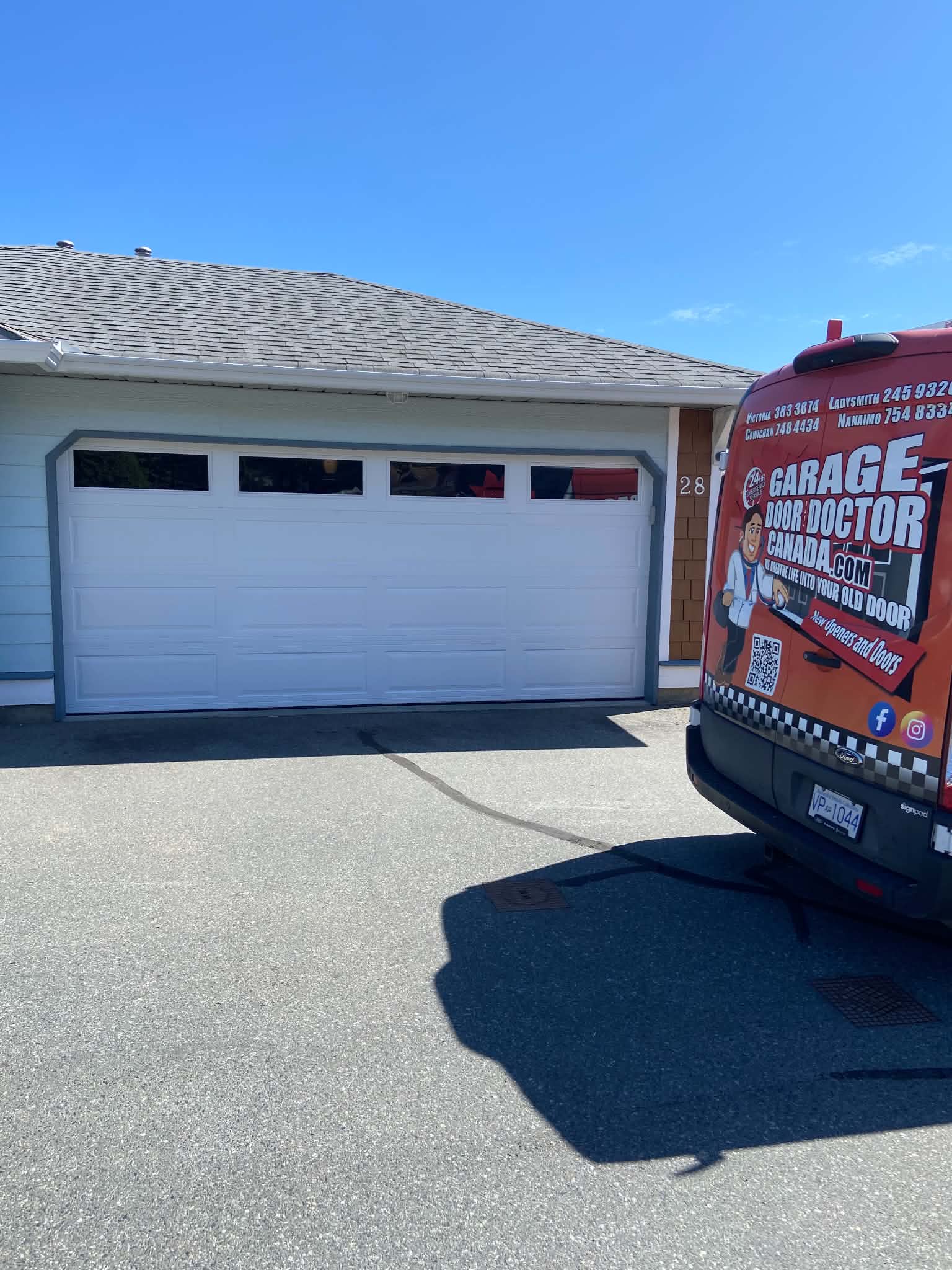 Newly installed white double garage door with the Garage Door Doctor Canada service van in the driveway