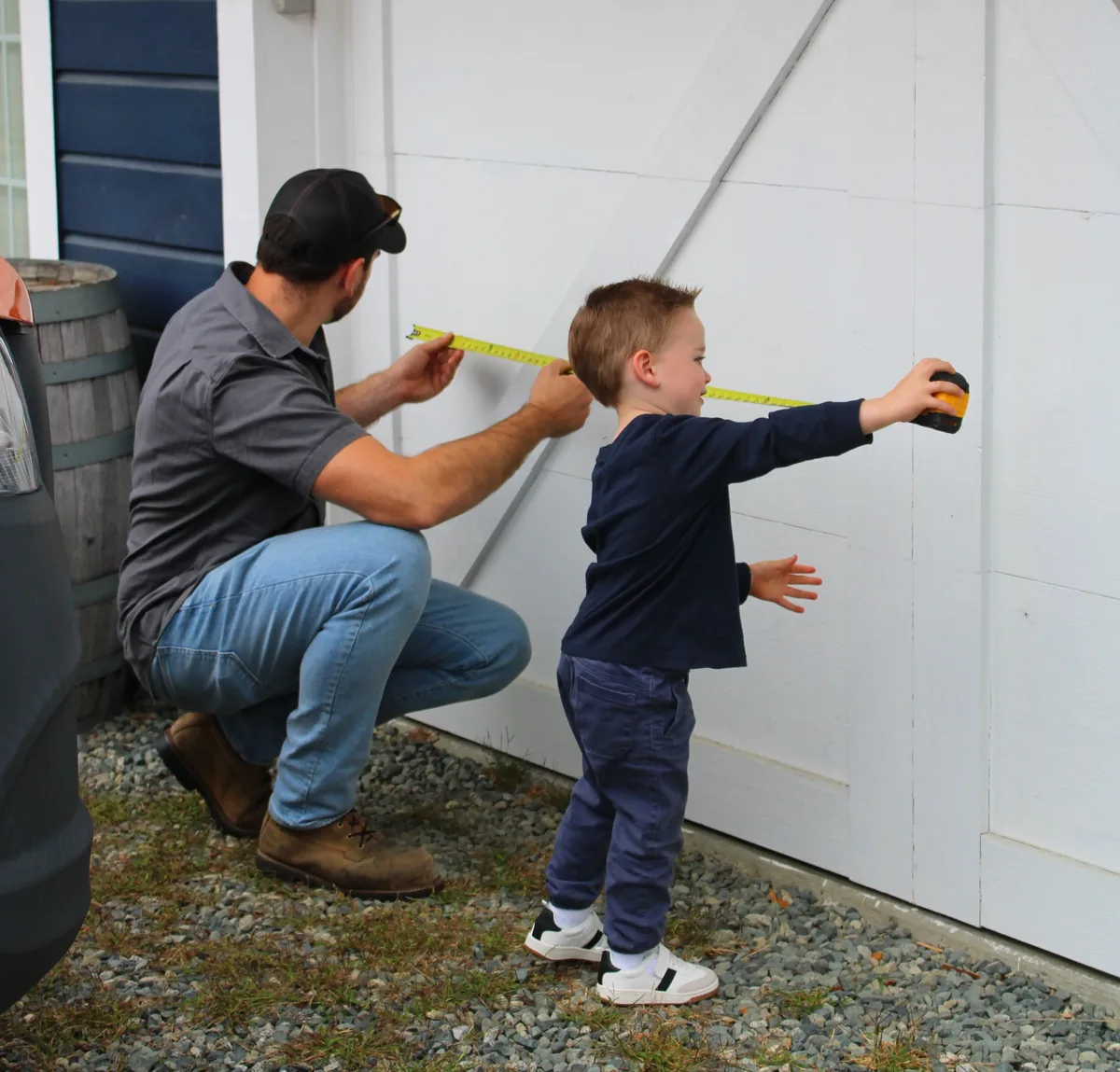 Garage Door Doctor Canada co-owner measuring a new garage door with his young son helping