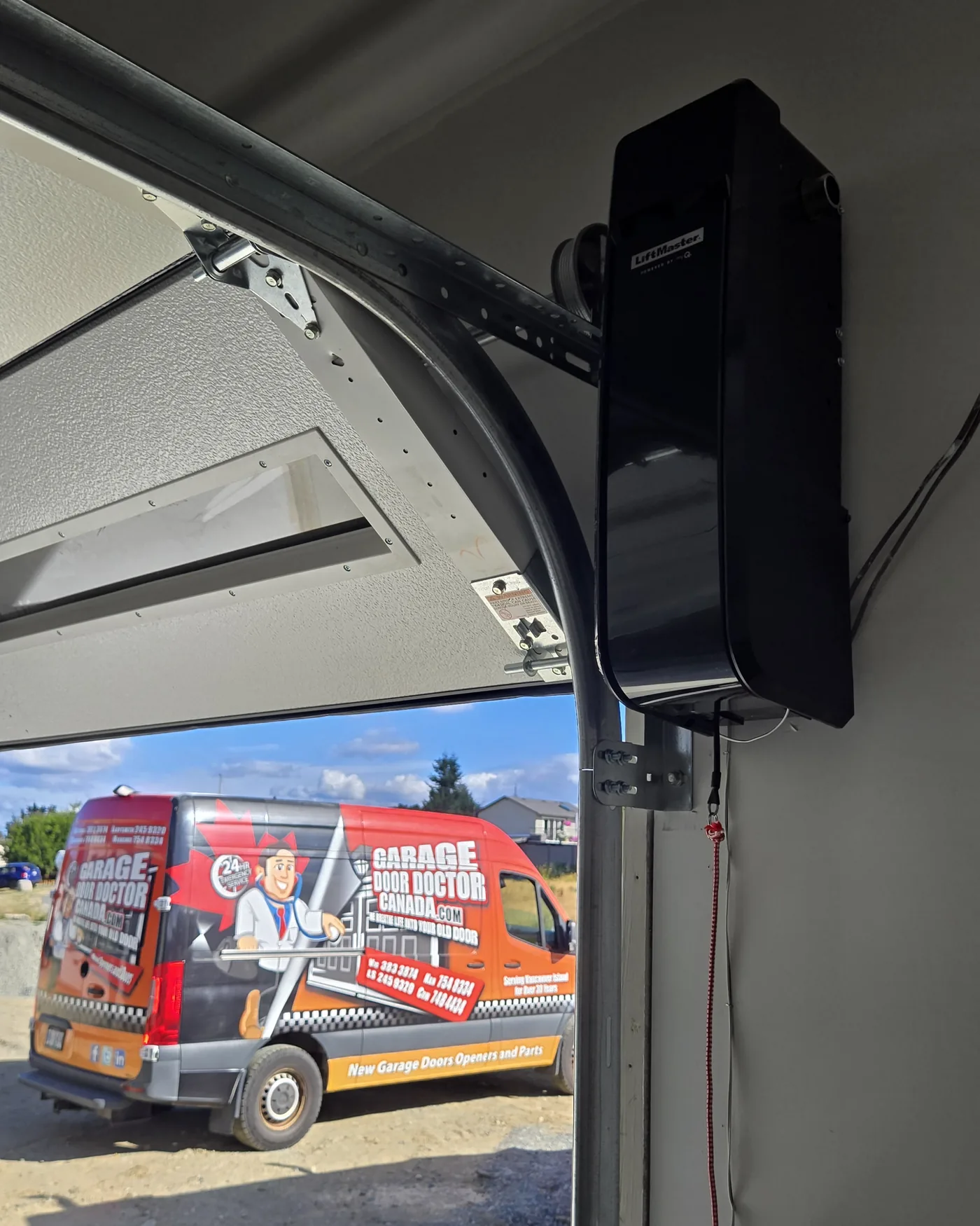 Garage Door Doctor Canada service van parked outside an open garage door, with a LiftMaster wall-mount opener installed inside